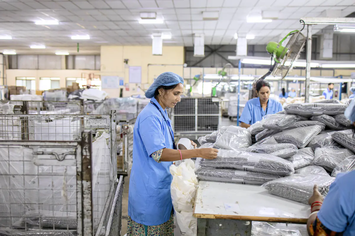 Workers in blue uniforms sorting and packing goods on a factory floor